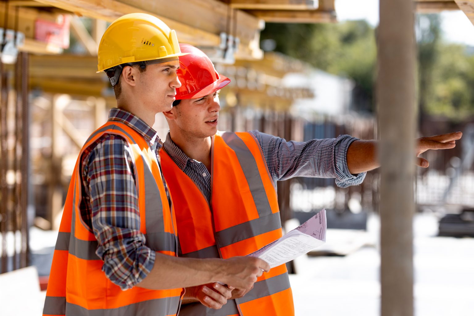 Two civil engineers dressed in orange work vests and helmets